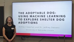 Ashley Llewellyn standing next to presention slides with title "The Adoptable Dog: Using Machine Learning to Explore Shelter Dog Adoption".